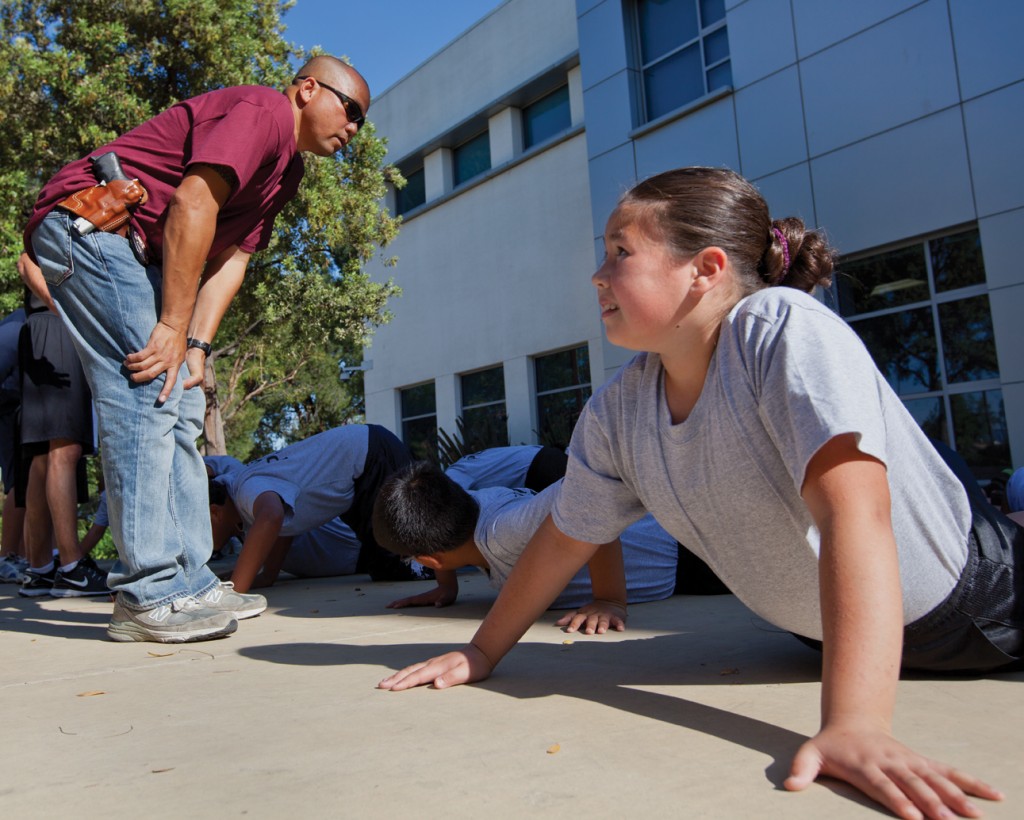 Officer Edison Vistar pushes Alicia Ontiveros  for one more pushup outside the West Valley Community Police Station in Reseda,Calif. April 18, 2012. Elementary and middle school students attend the biweekly workouts.